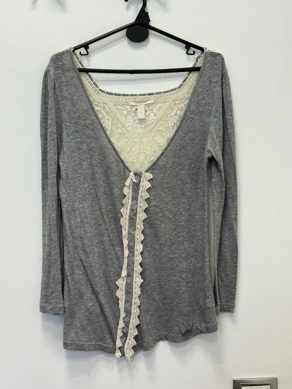 Blusa gris con detalle de encaje en la espalda y en el frente. Manga larga. Talle 44.