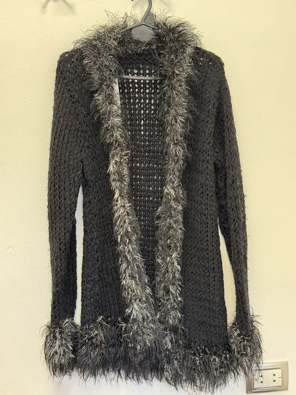 Cardigan negro tejido con detalles de peluche gris en cuello, borde y puños. Ideal para un look elegante y abrigado.