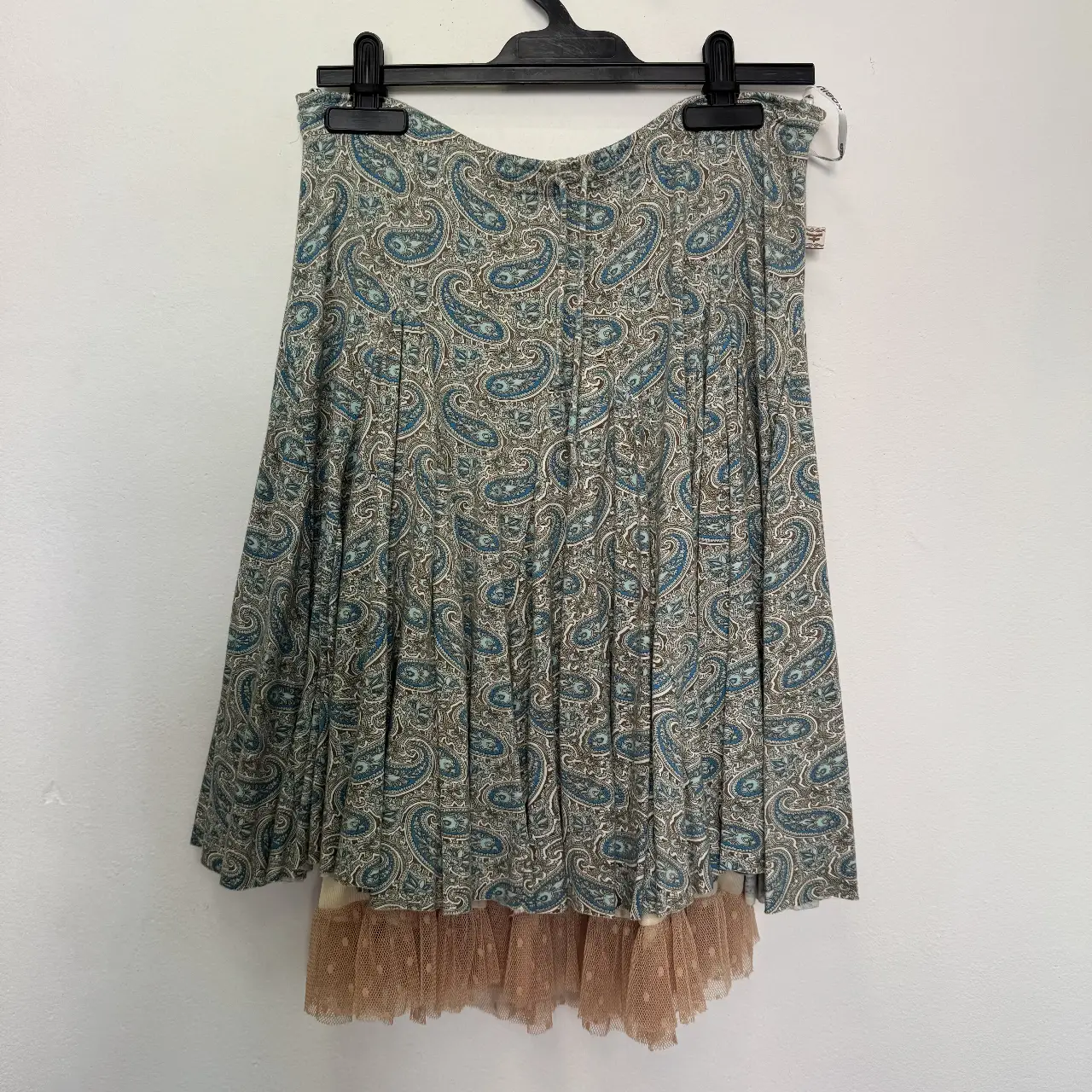 Pollera midi con estampado paisley en tonos azules y marrones. Cuenta con un forro de tul color durazno que le da un toque romántico y delicado. Ideal para un look casual con un toque vintage.