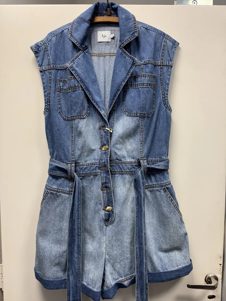 Mono corto de jean con cinturón. Posee botones dorados y bolsillos delanteros y traseros. Ideal para un look casual y moderno.