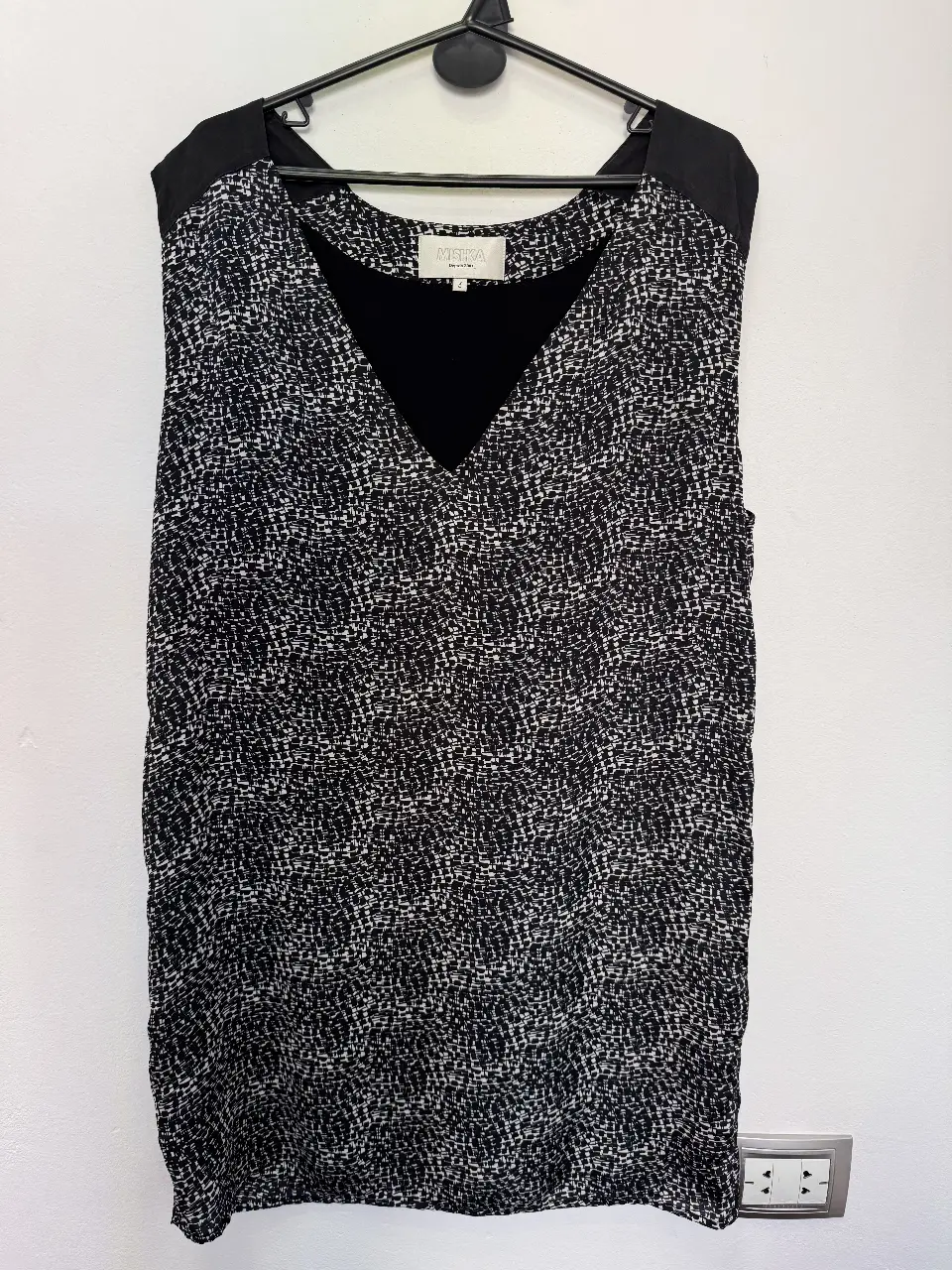 Vestido mini con estampado en blanco y negro, escote en V y detalles en negro en los hombros. Ideal para una salida casual o evento.