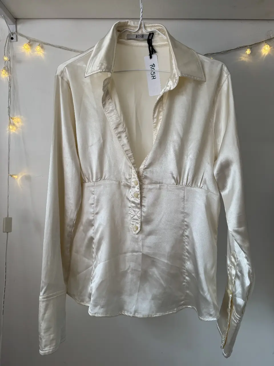 Blusa de seda color crudo, con cuello camisero y botones. Ideal para un look elegante y sofisticado.