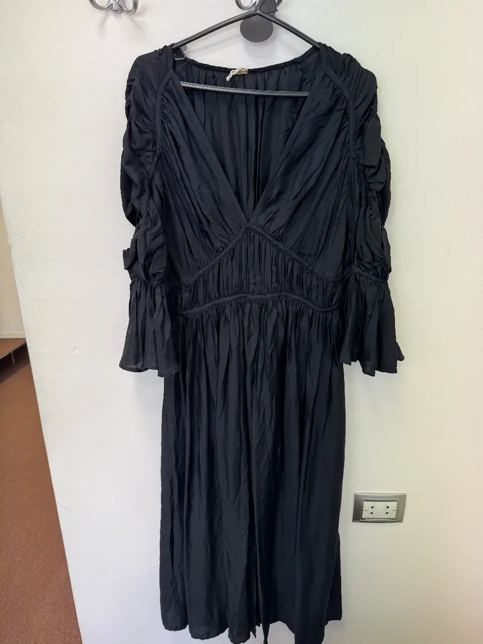 Vestido midi negro con escote en V y mangas con volados. Diseño drapeado en el busto y cintura, ideal para eventos especiales o salidas nocturnas.