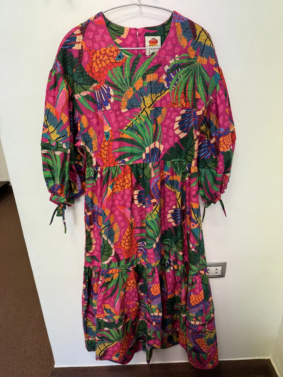 Vestido largo de mujer con estampado tropical, mangas largas abullonadas y detalles de lazos en los puños. Ideal para un look bohemio y fresco.