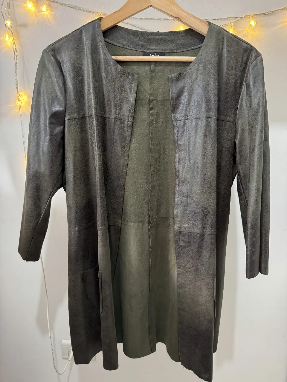 Elegante blazer largo de Joela, en un tono gris verdoso con un diseño de cuero sintético. Ideal para un look sofisticado y moderno.
