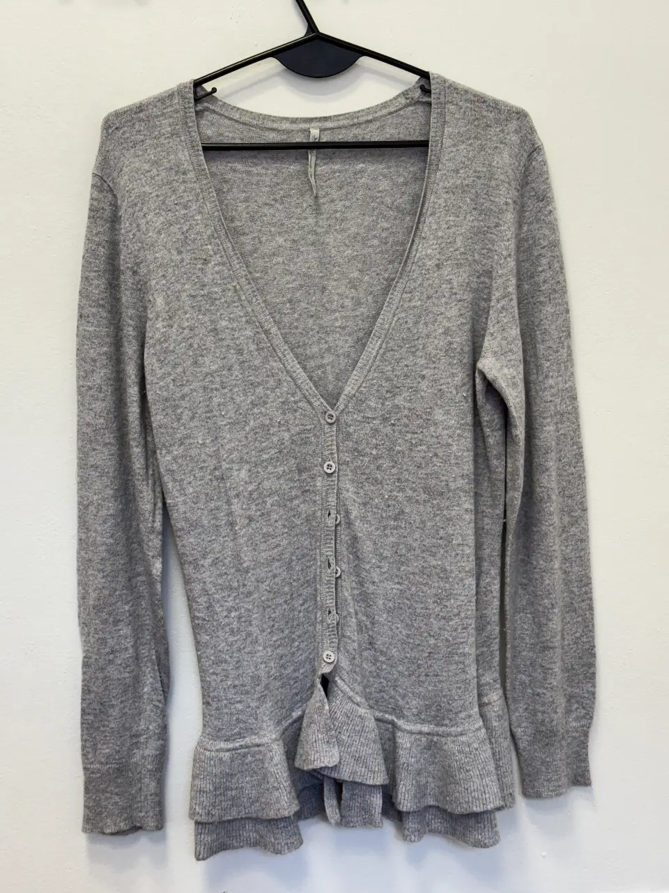 Cardigan gris de mujer, con cuello en V y detalle de volados en el bajo. Ideal para un look casual y cómodo.