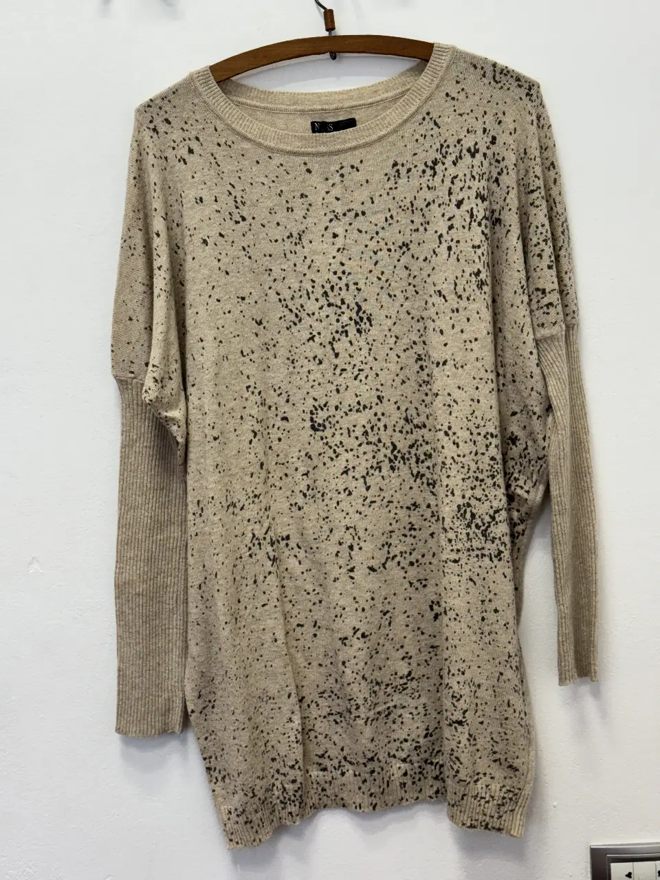 Sweater largo de punto con diseño salpicado en color crudo y detalles en negro. Ideal para un look casual y cómodo.