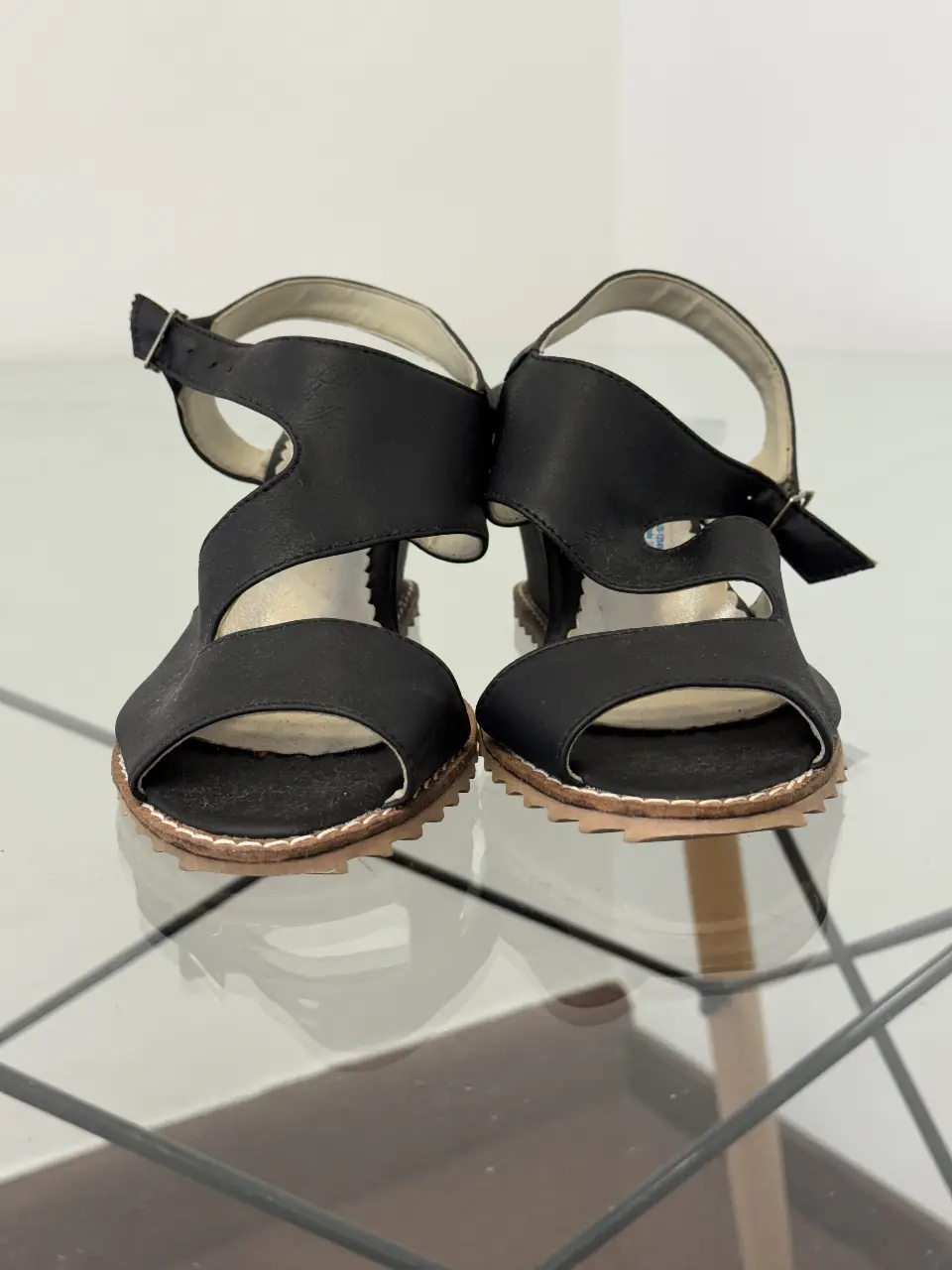 Sandalias negras con diseño moderno y detalles en la suela. Ideales para un look casual y cómodo.