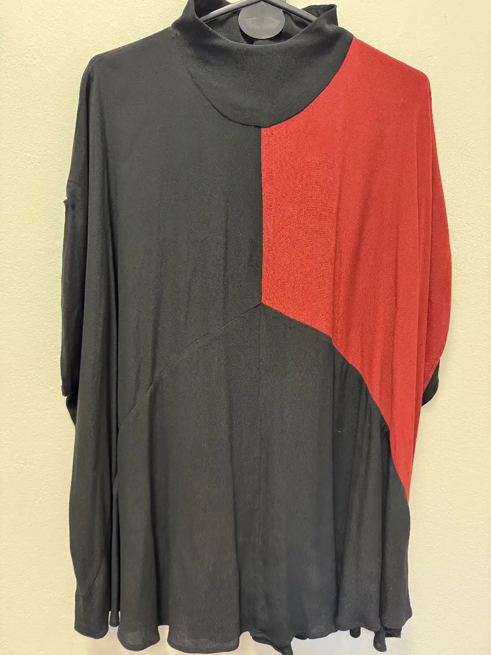 Blusa de diseño asimétrico en dos colores, negro y rojo. Cuello alto y corte holgado. Ideal para un look moderno y sofisticado.