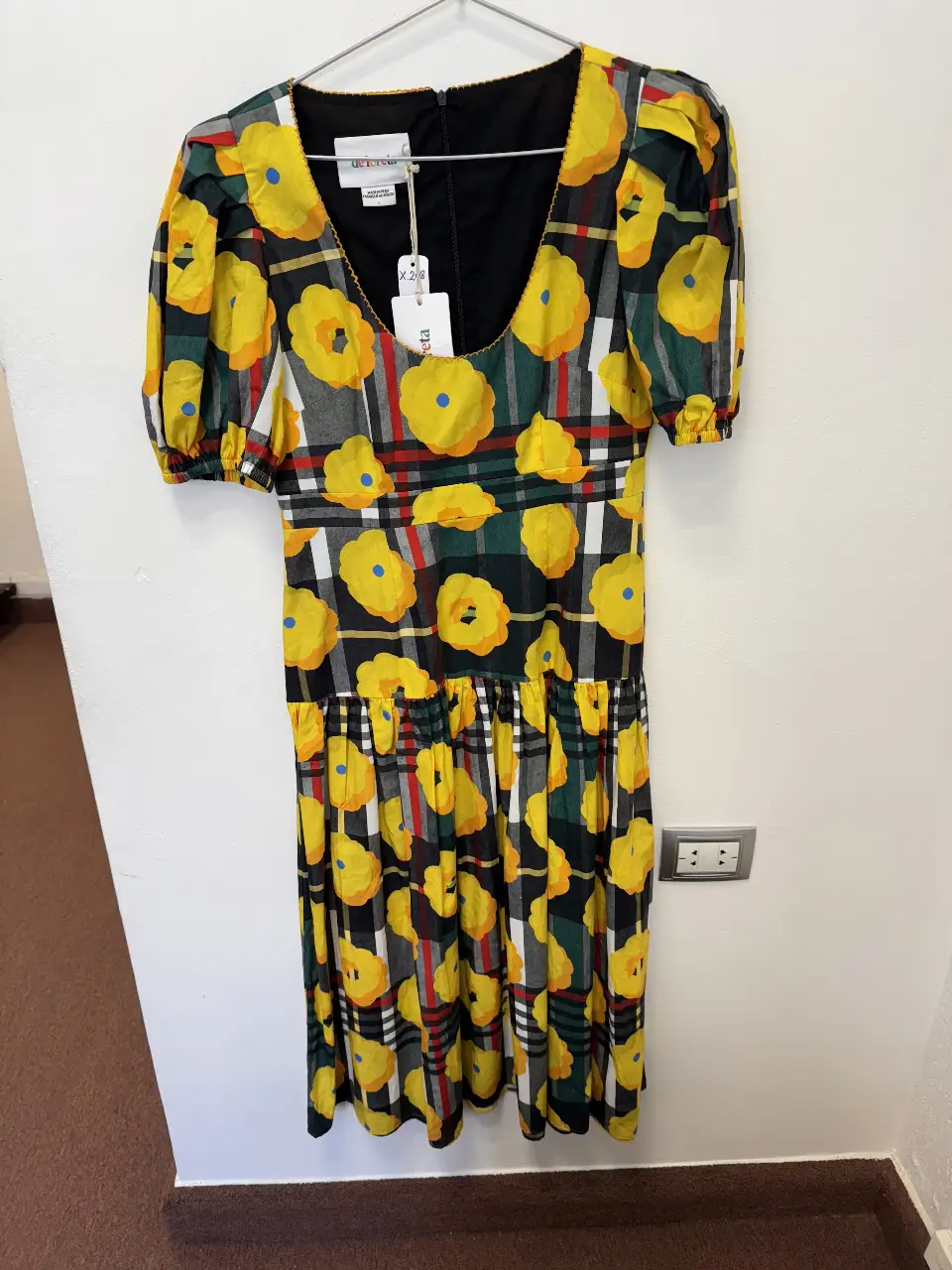 Vestido midi con estampado floral amarillo sobre fondo negro y detalles a cuadros. Diseño con mangas cortas abullonadas y falda con vuelo. Ideal para un look fresco y con estilo.