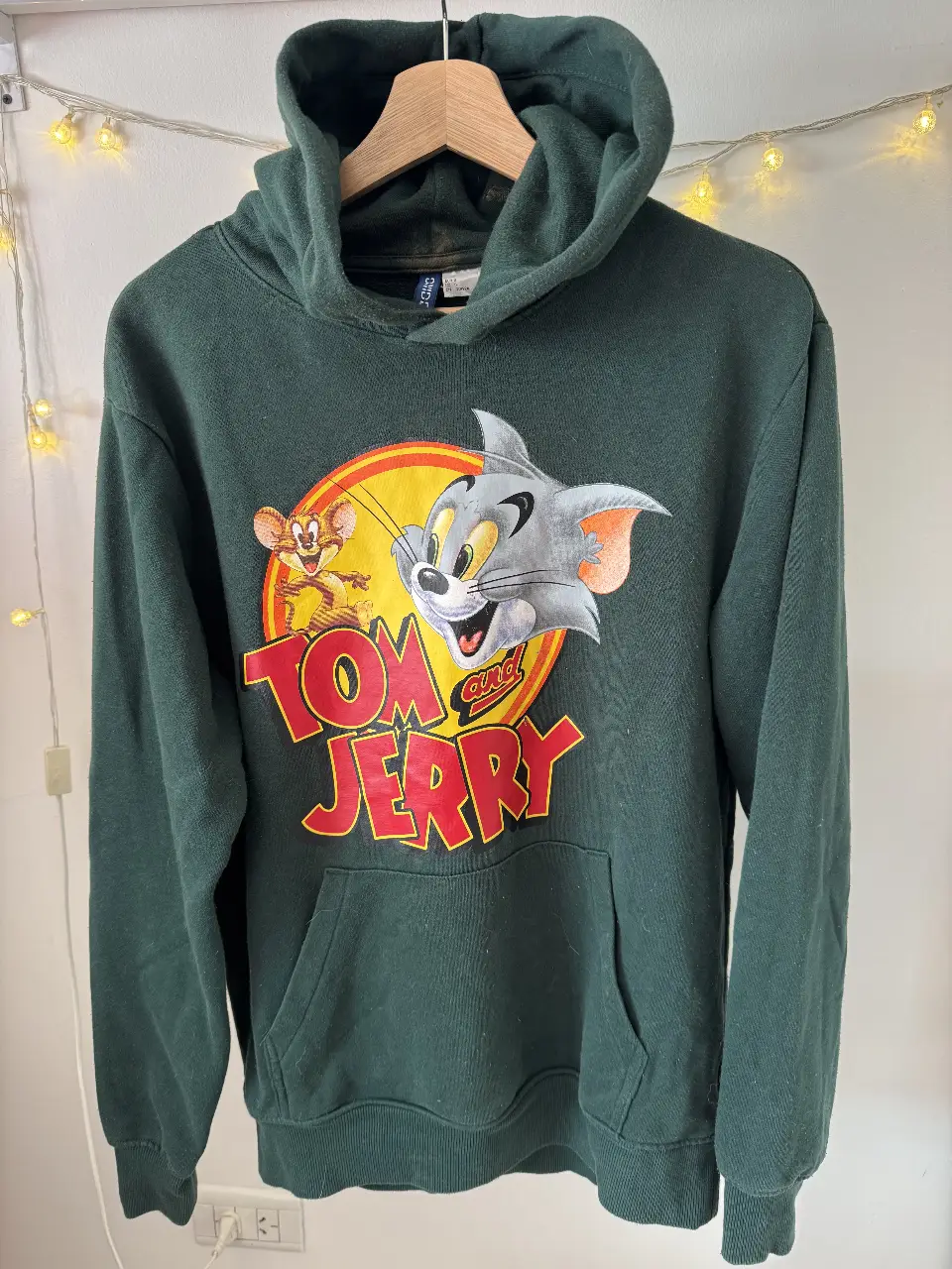 Buzo canguro verde oscuro de H&M con estampado de Tom y Jerry. Ideal para un look casual y cómodo.