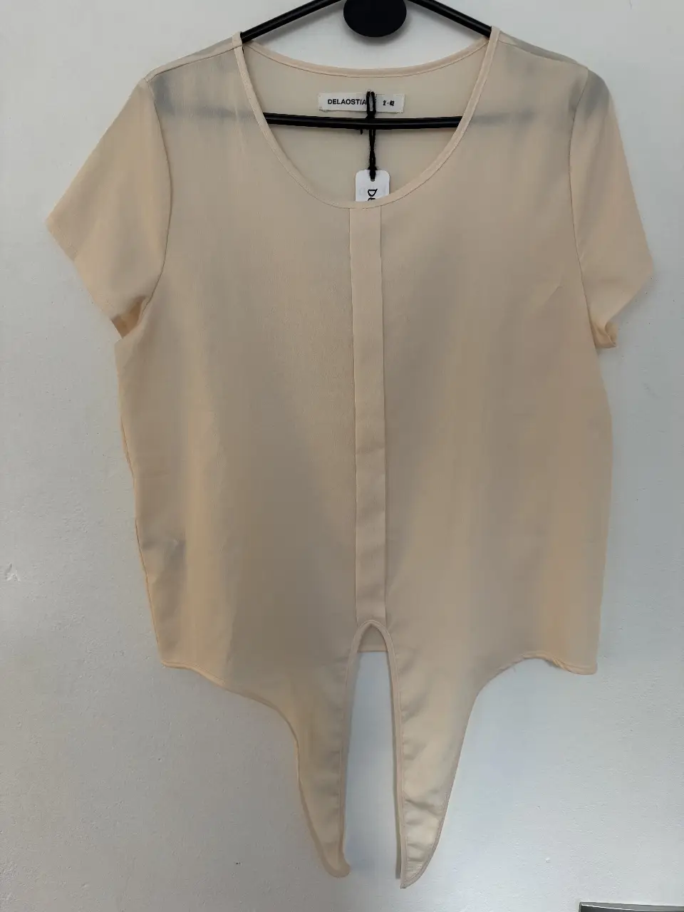 Blusa de tela liviana color crudo, con mangas cortas y detalle de lazo en la parte delantera. Ideal para un look casual y fresco.