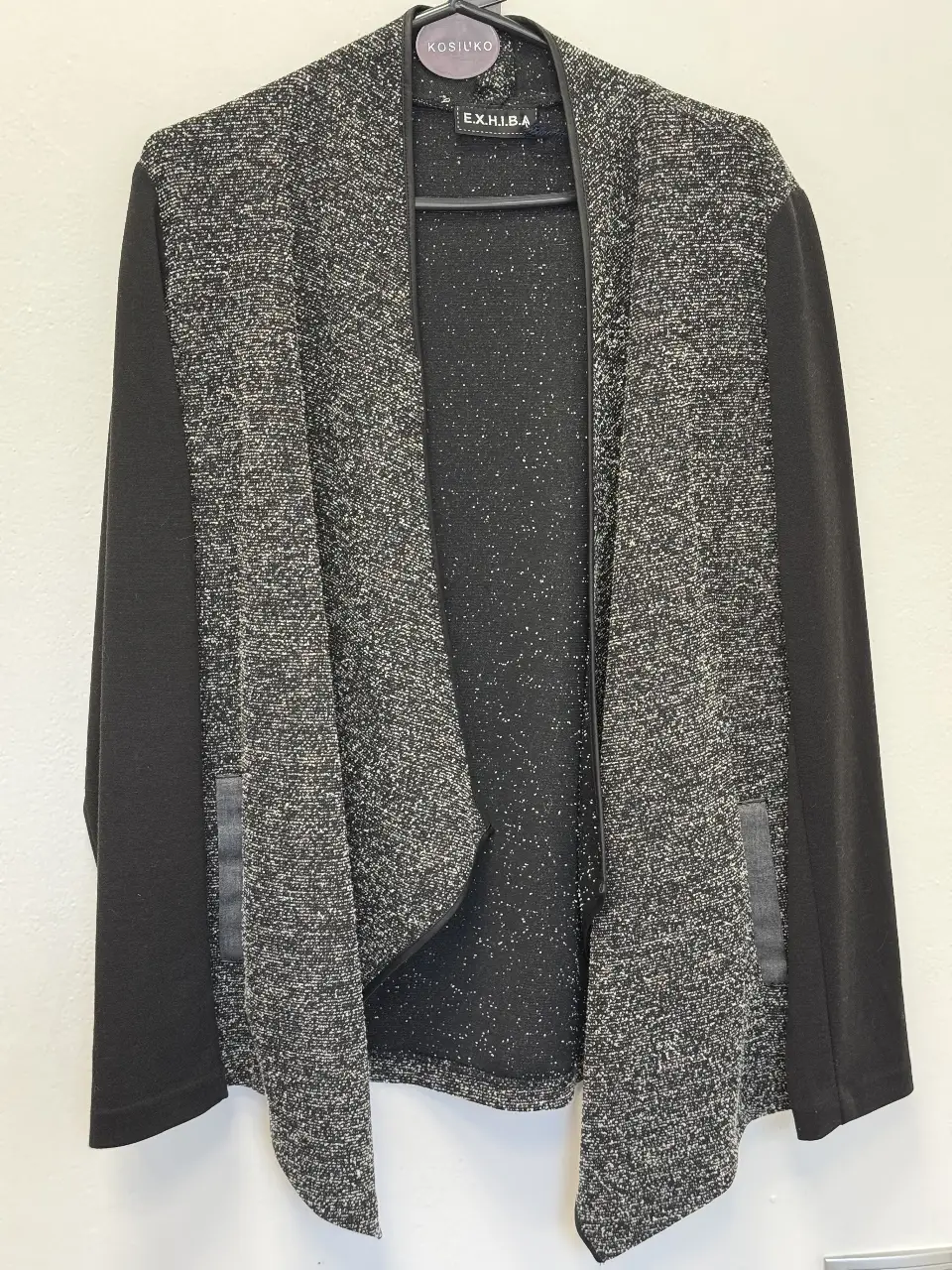 Cardigan de mujer con diseño jaspeado en tonos grises y negro. Mangas y laterales en negro liso. Ideal para un look casual y moderno.