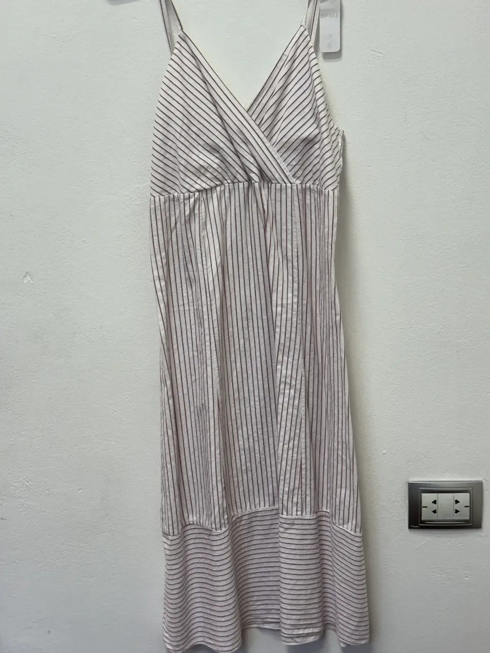 Vestido midi a rayas verticales en blanco y rojo. Diseño con escote en V cruzado y tirantes finos. Ideal para un look fresco y veraniego.
