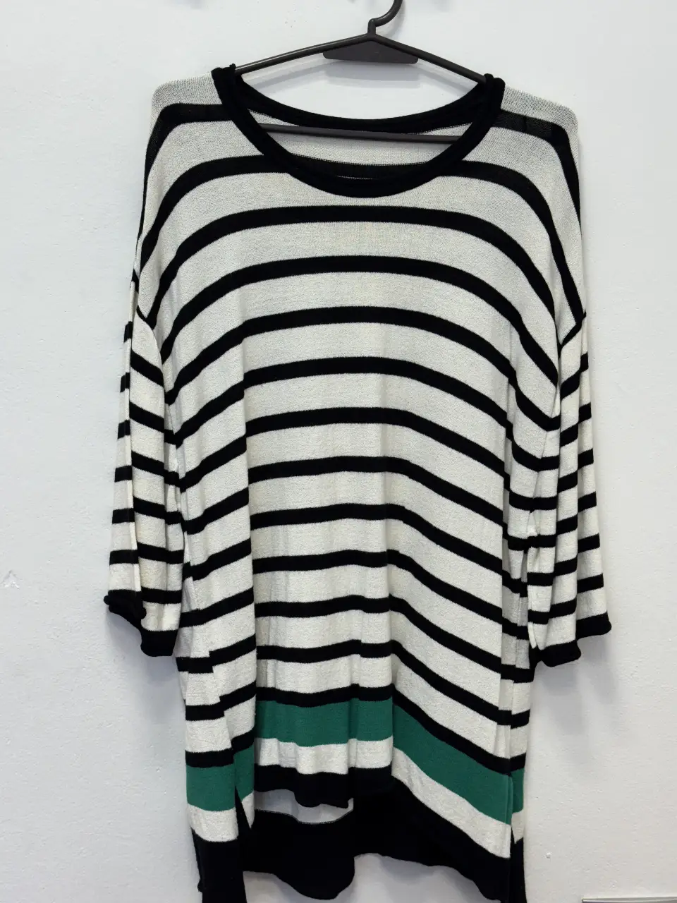 Sweater largo a rayas horizontales en blanco y negro, con detalle de franja verde en el bajo. Cuello redondo y mangas 3/4. Ideal para un look casual y cómodo.