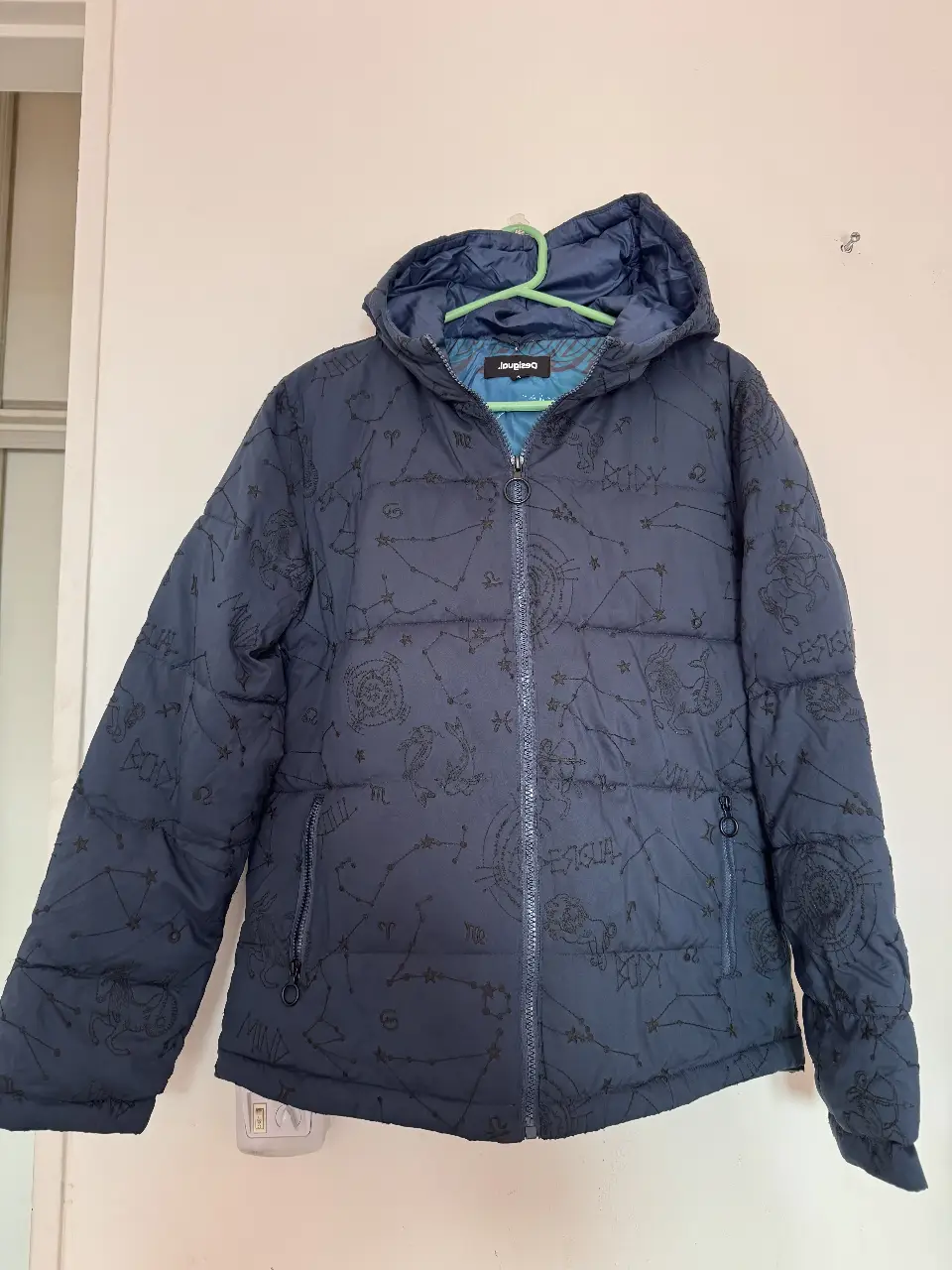 Campera Desigual azul marino con estampado de constelaciones. Posee capucha, cierre frontal y bolsillos con cierre. Ideal para el invierno.