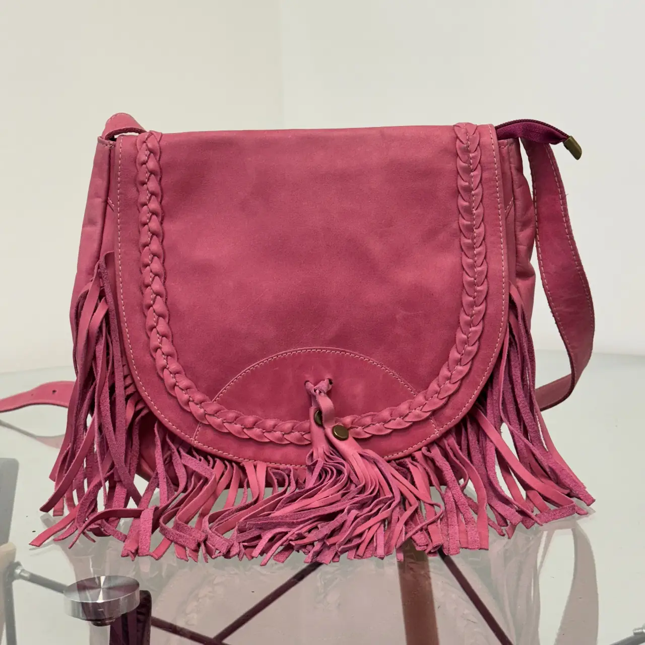 Cartera bandolera de gamuza rosa con flecos y detalles trenzados. Ideal para un look boho chic.