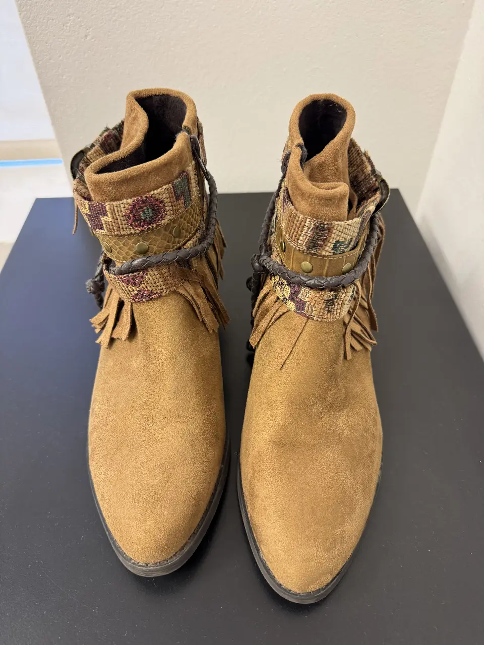Botines de gamuza marrón con detalles boho. Tienen flecos y cintas decorativas en el tobillo. Ideales para un look casual y con onda.