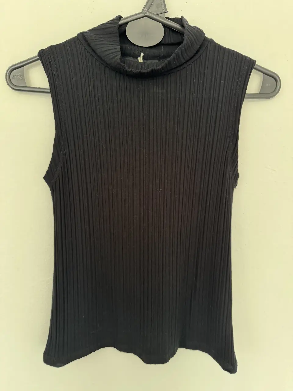Musculosa de cuello alto, de tejido acanalado, ideal para un look casual y moderno. Perfecta para combinar con jeans o pantalones de vestir.