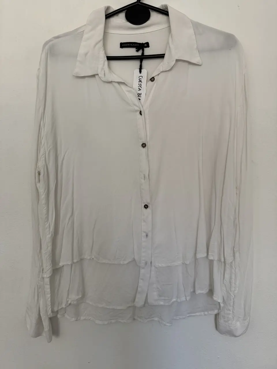 Blusa blanca de mujer, con diseño de doble capa y botones. Ideal para un look casual y elegante.