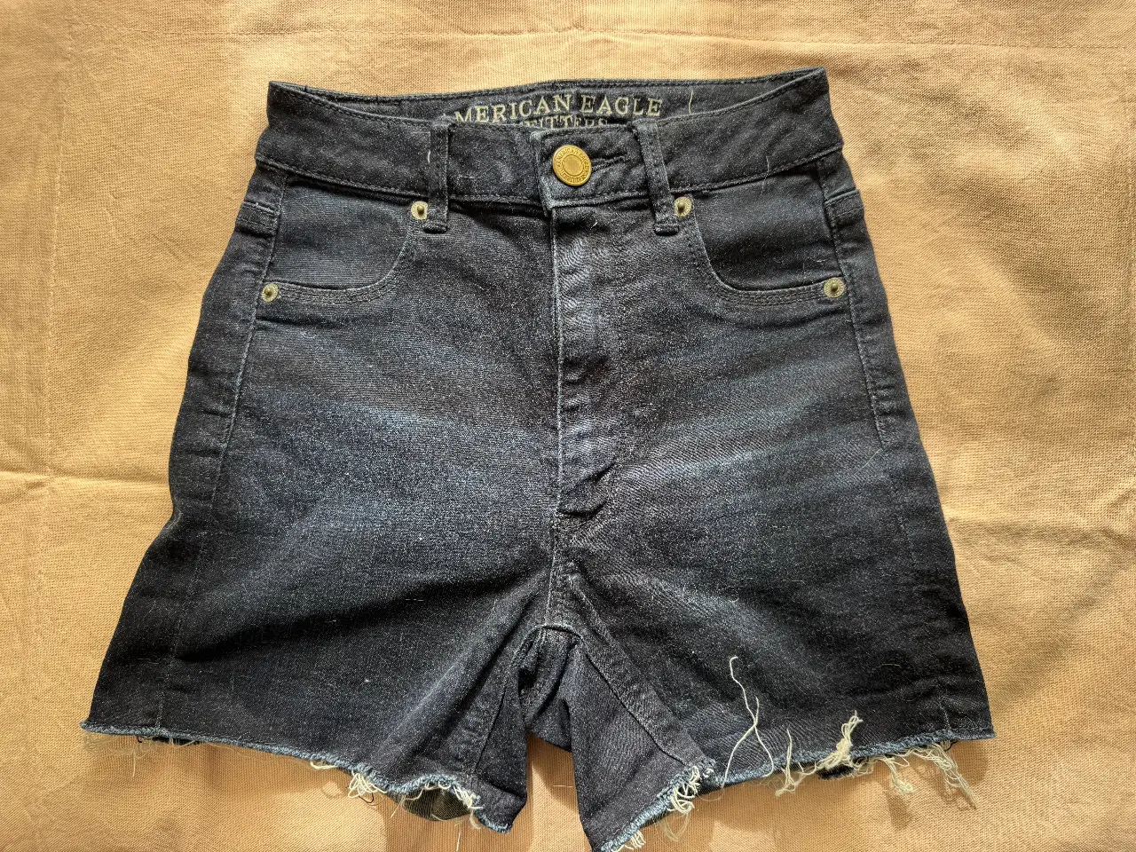 Short de jean de mujer, tiro alto, con bordes desflecados. Marca American Eagle.