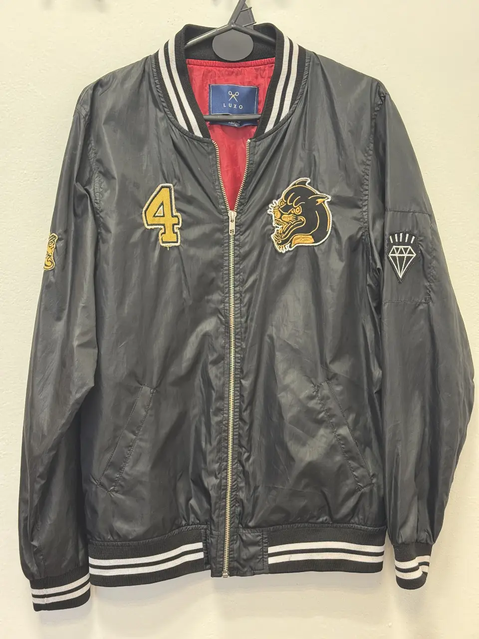 Campera bomber negra con detalles en blanco y dorado. Tiene parches con el número 4 y un diseño de pantera. Ideal para un look casual y canchero.
