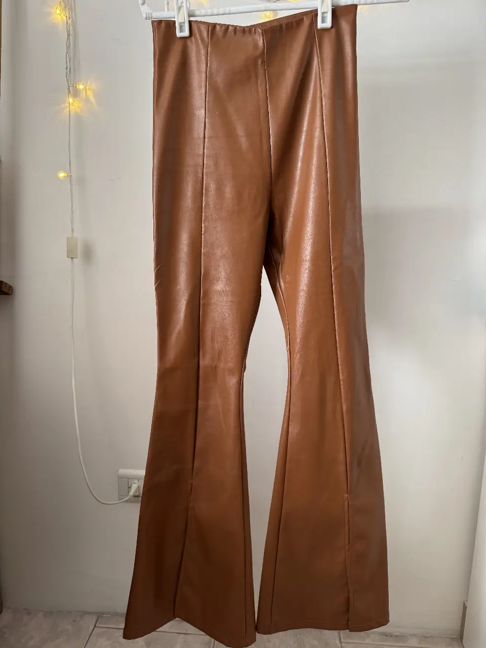 Pantalón de cuero sintético marrón con corte campana. Tiro alto y calce perfecto. Ideal para un look moderno y sofisticado.