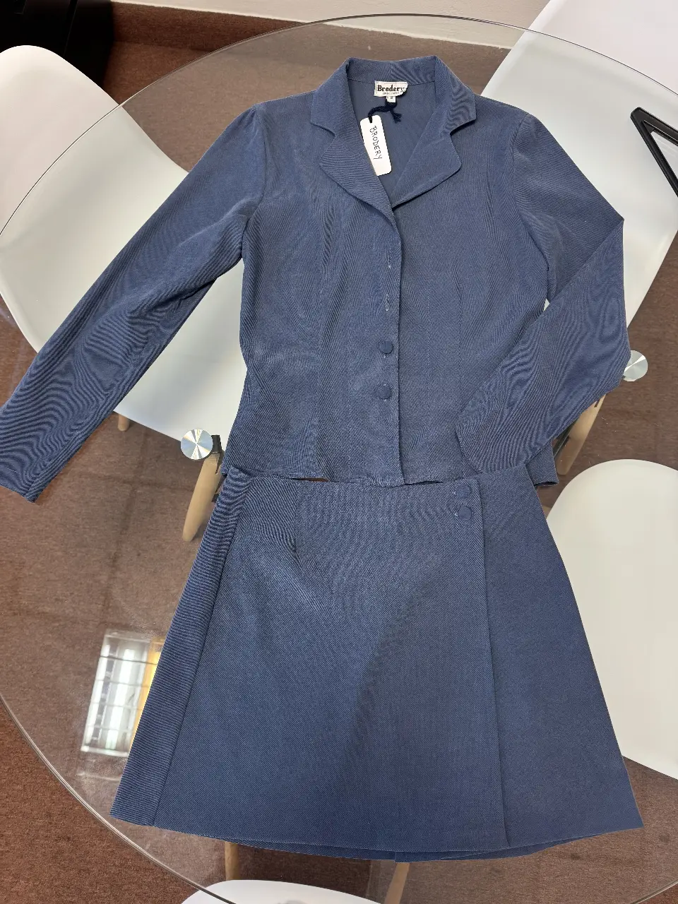 Conjunto de blazer y pollera sastreros de color azul. El blazer tiene solapas y botones, mientras que la pollera es de corte recto.