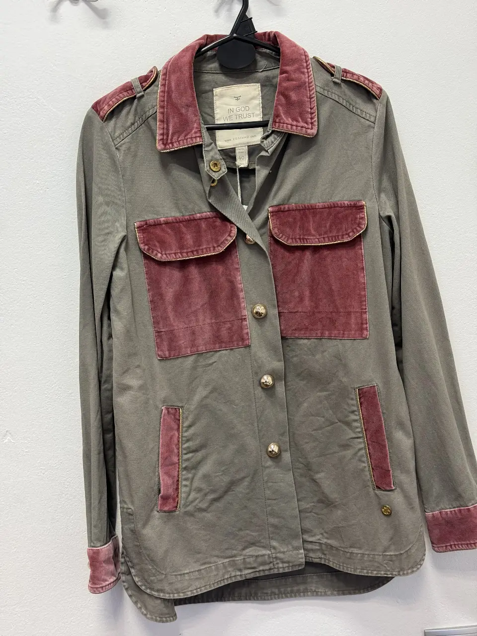 Camisa de mujer de color gris con detalles en rojo, incluyendo bolsillos y cuello de terciopelo. Con botones dorados y etiqueta de la marca 'In God We Trust'. Talle 40.