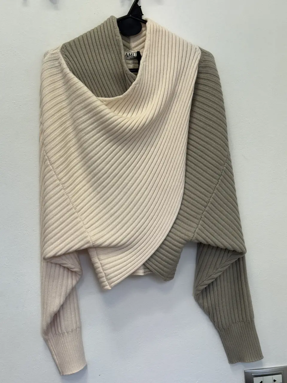Sweater largo de diseño asimétrico en dos tonos, con cuello alto y mangas largas. Ideal para un look moderno y abrigado.