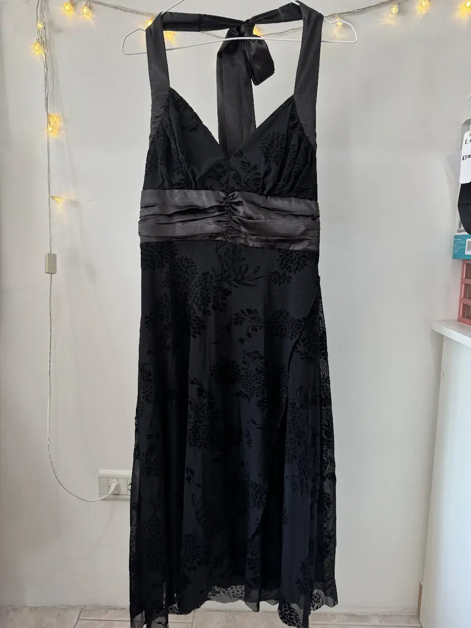 Vestido largo negro con detalles florales en relieve. Diseño elegante con escote en V y lazo en la espalda. Ideal para eventos formales y fiestas.