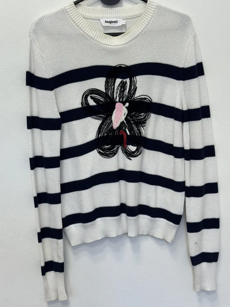 Sweater de mujer a rayas horizontales blancas y azul marino, con un diseño floral en el centro. Ideal para un look casual y cómodo.