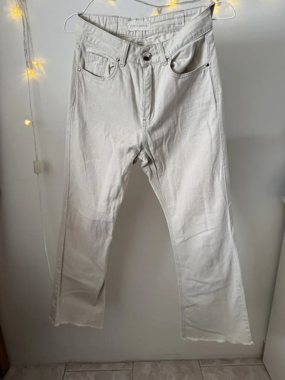 Jeans rectos color crudo, tiro medio, con detalles de costura y terminación desflecada en el bajo. Un clásico versátil para cualquier ocasión.