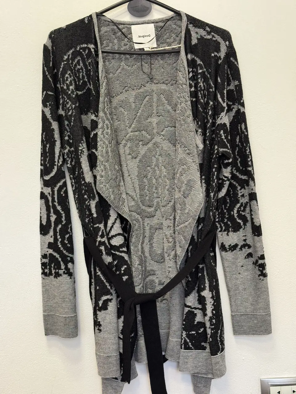 Cardigan largo de mujer, con diseño floral en tonos grises y negros. Incluye cinturón para ajustar la cintura. Ideal para un look casual y elegante.