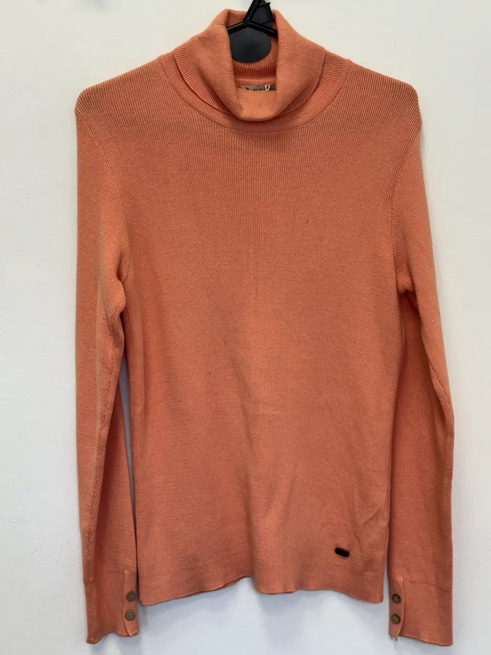 Sweater de cuello alto color naranja, ideal para el invierno. Con detalles de botones en los puños y un pequeño logo de la marca GENOA. Perfecto para un look casual y abrigado.