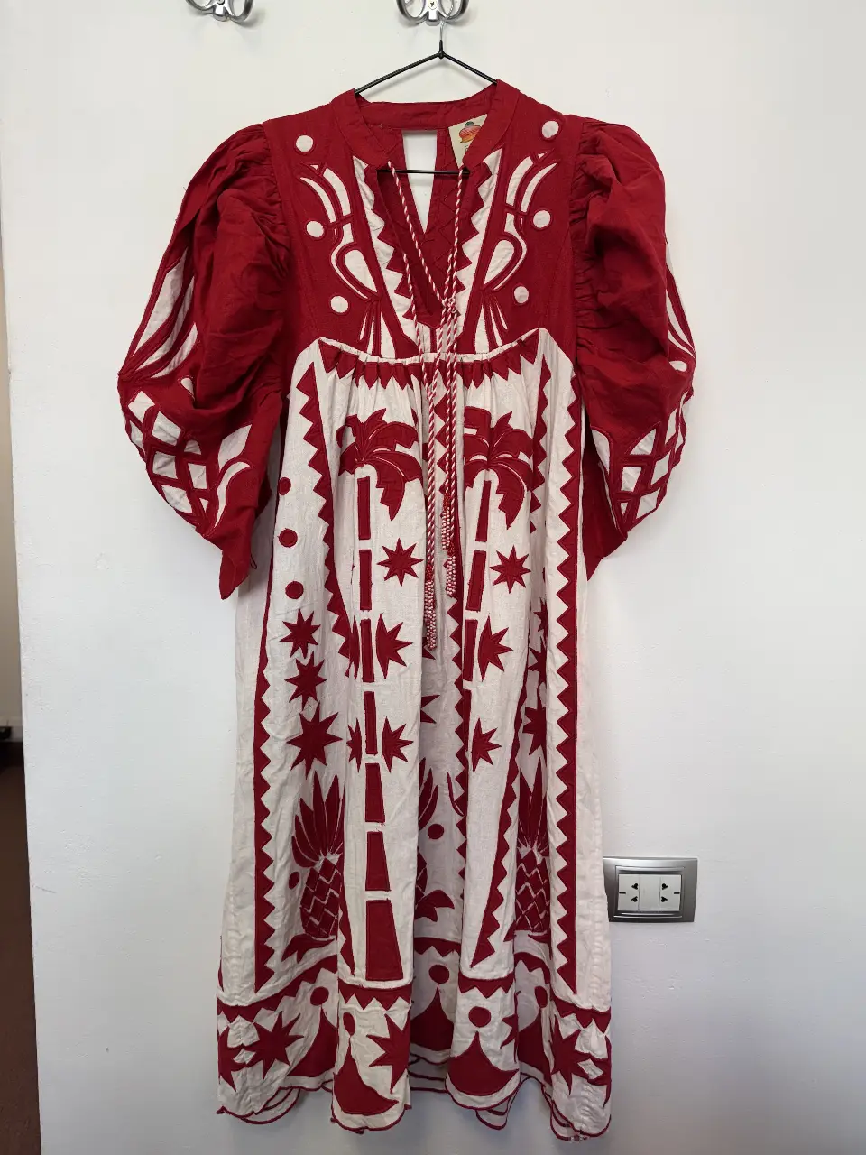 Vestido midi de algodón con estampado artesanal en rojo y blanco. Diseño con mangas abullonadas y detalles bordados. Ideal para un look bohemio y casual.