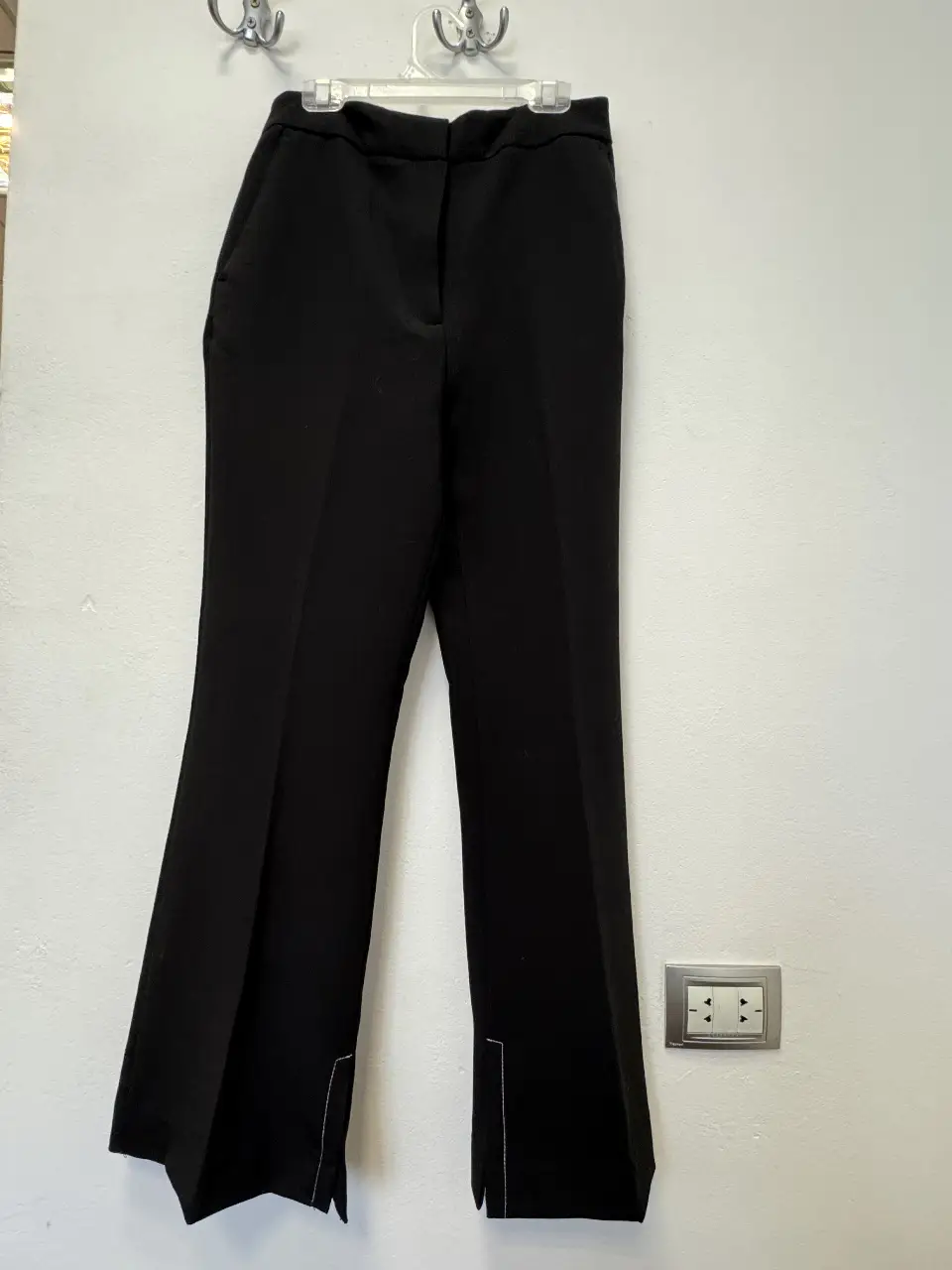 Pantalón sastrero negro de Zara, con corte recto y detalle de abertura en el bajo. Talle 28.