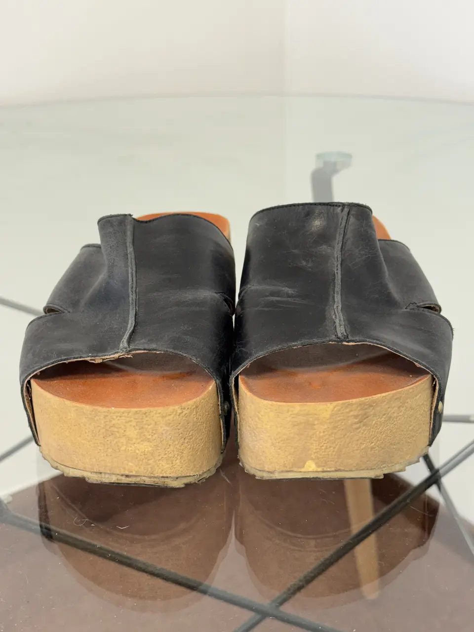 Sandalias de plataforma con base de madera y capellada de cuero negro. Un clásico de los 70s, ideales para un look retro.