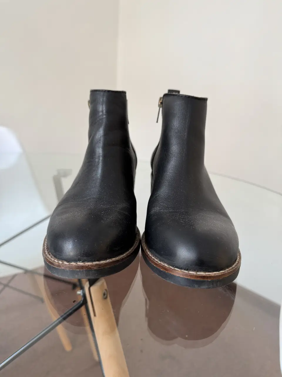 Botines negros de cuero con cierre lateral y suela marrón. Ideales para un look casual y moderno.