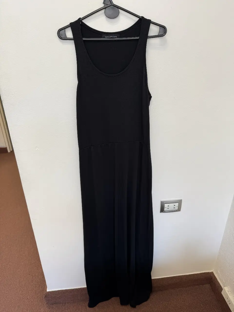Vestido largo negro, de tela suave y caída fluida. Diseño liso, sin mangas y con cintura marcada. Ideal para un look elegante y cómodo.