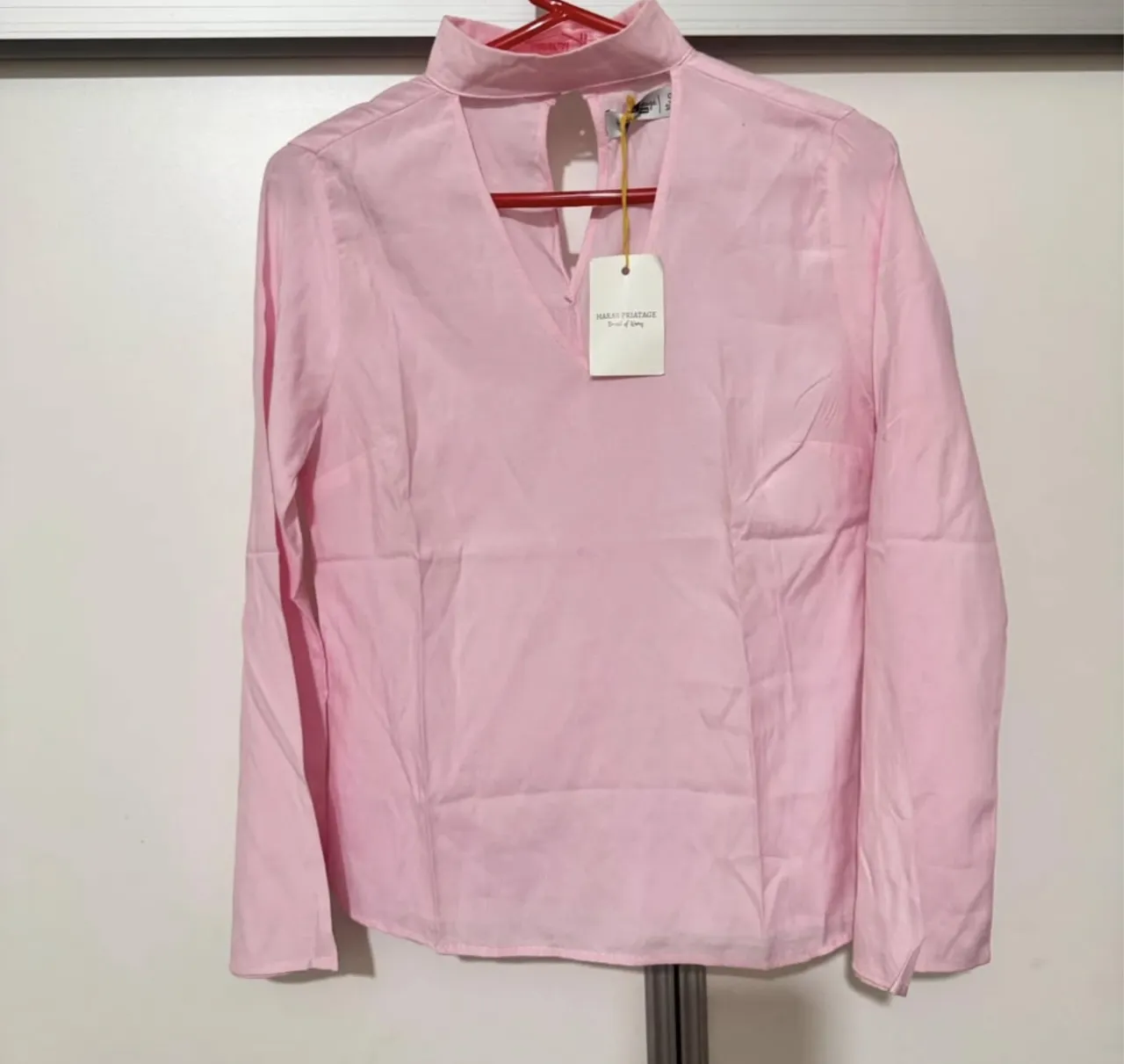 Blusa rosa con cuello alto y escote en V. Manga larga. Ideal para un look elegante y femenino.