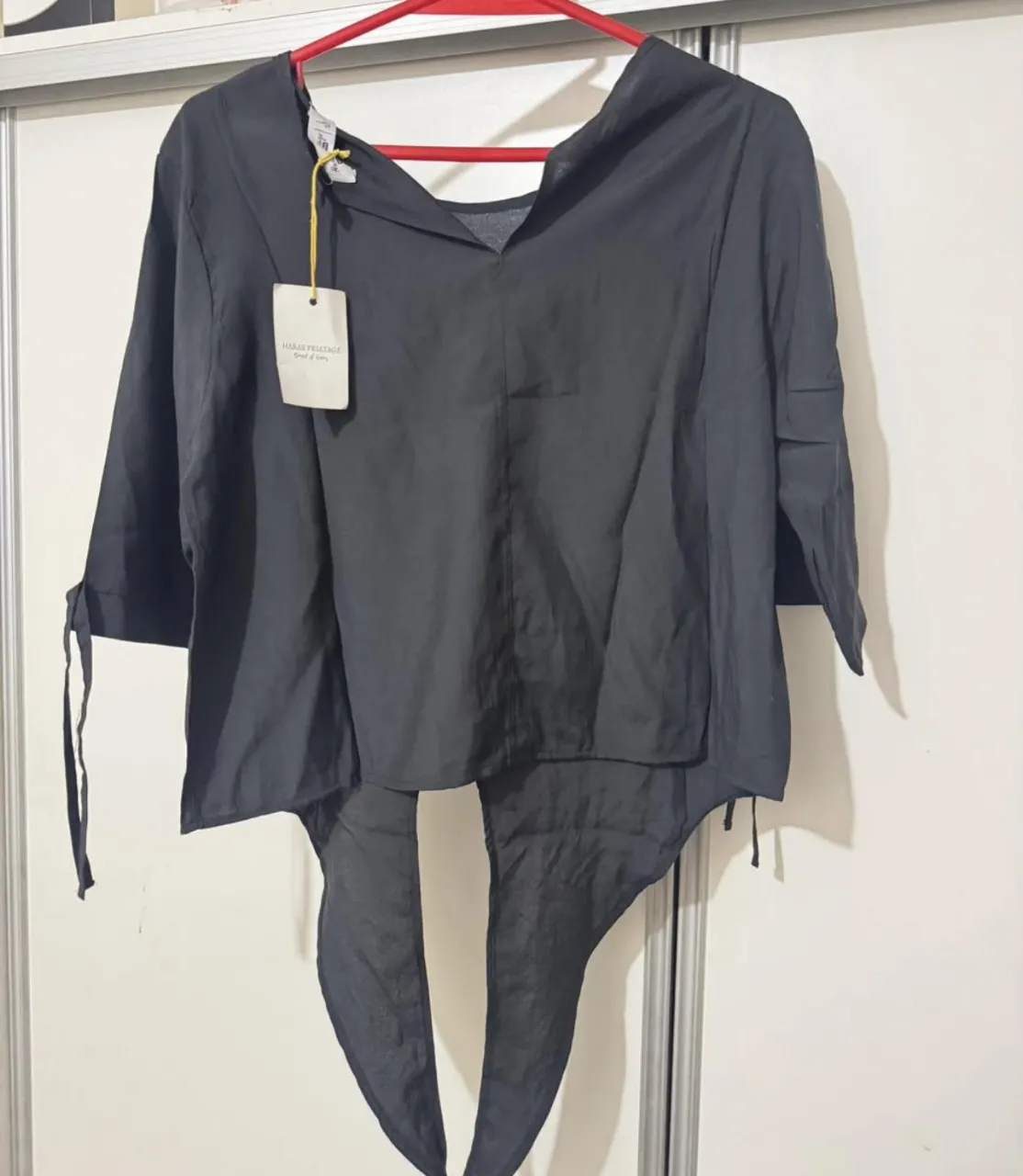 Blusa negra con mangas 3/4 y lazos en los puños.  Ideal para un look elegante y moderno.