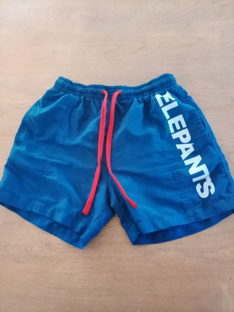 Shorts de baño azules con cordones rojos y estampa lateral de la marca. Ideales para disfrutar del verano y la playa.