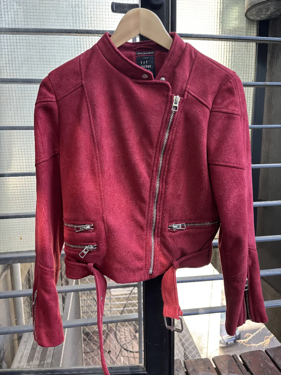 Campera estilo biker de gamuza roja para mujer. Con cierre asimétrico, bolsillos con cierre y cinturón. Ideal para un look moderno y audaz.