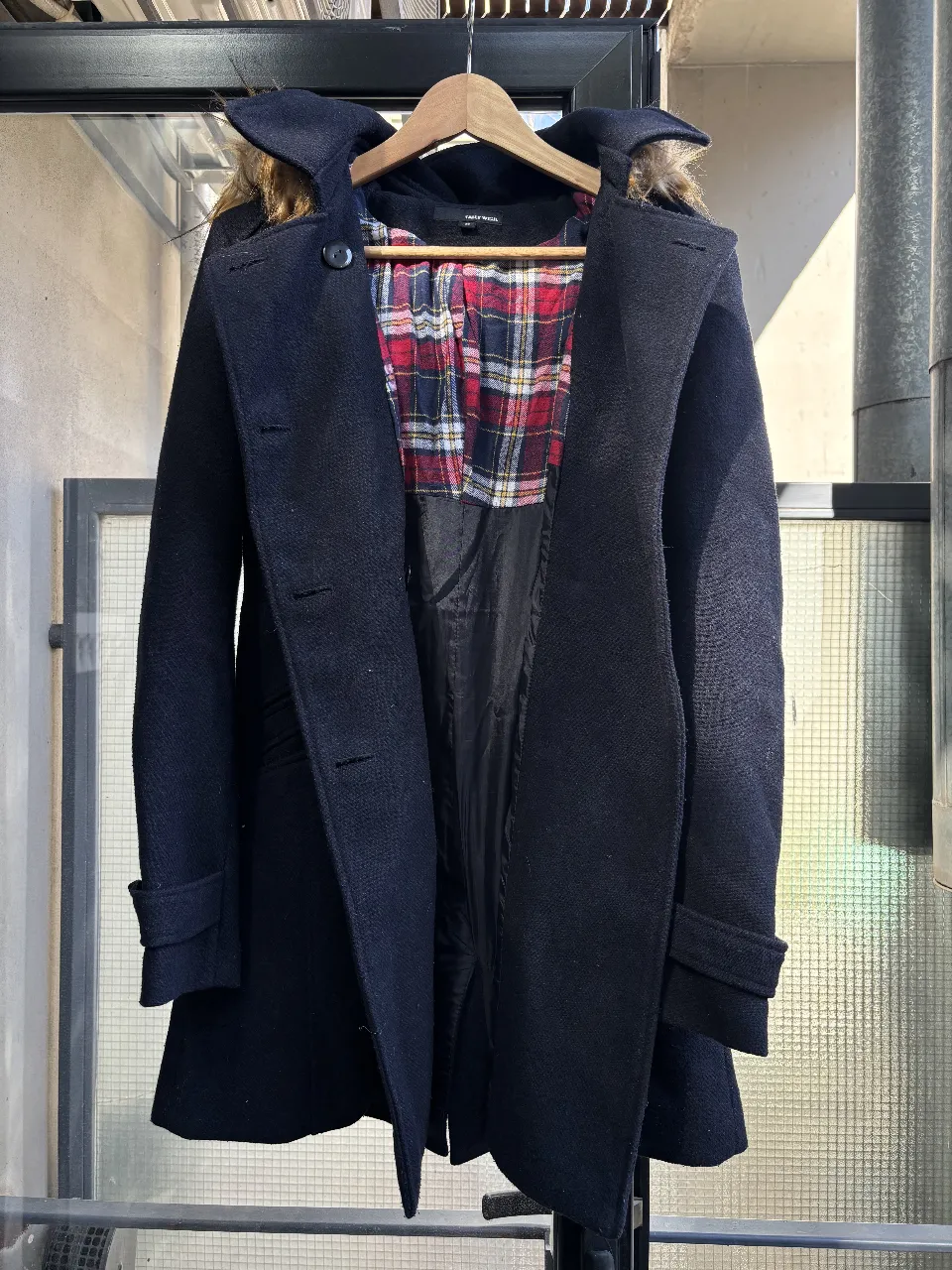 Tapado largo de paño negro con capucha y detalles de piel sintética. Interior a cuadros. Ideal para el invierno.