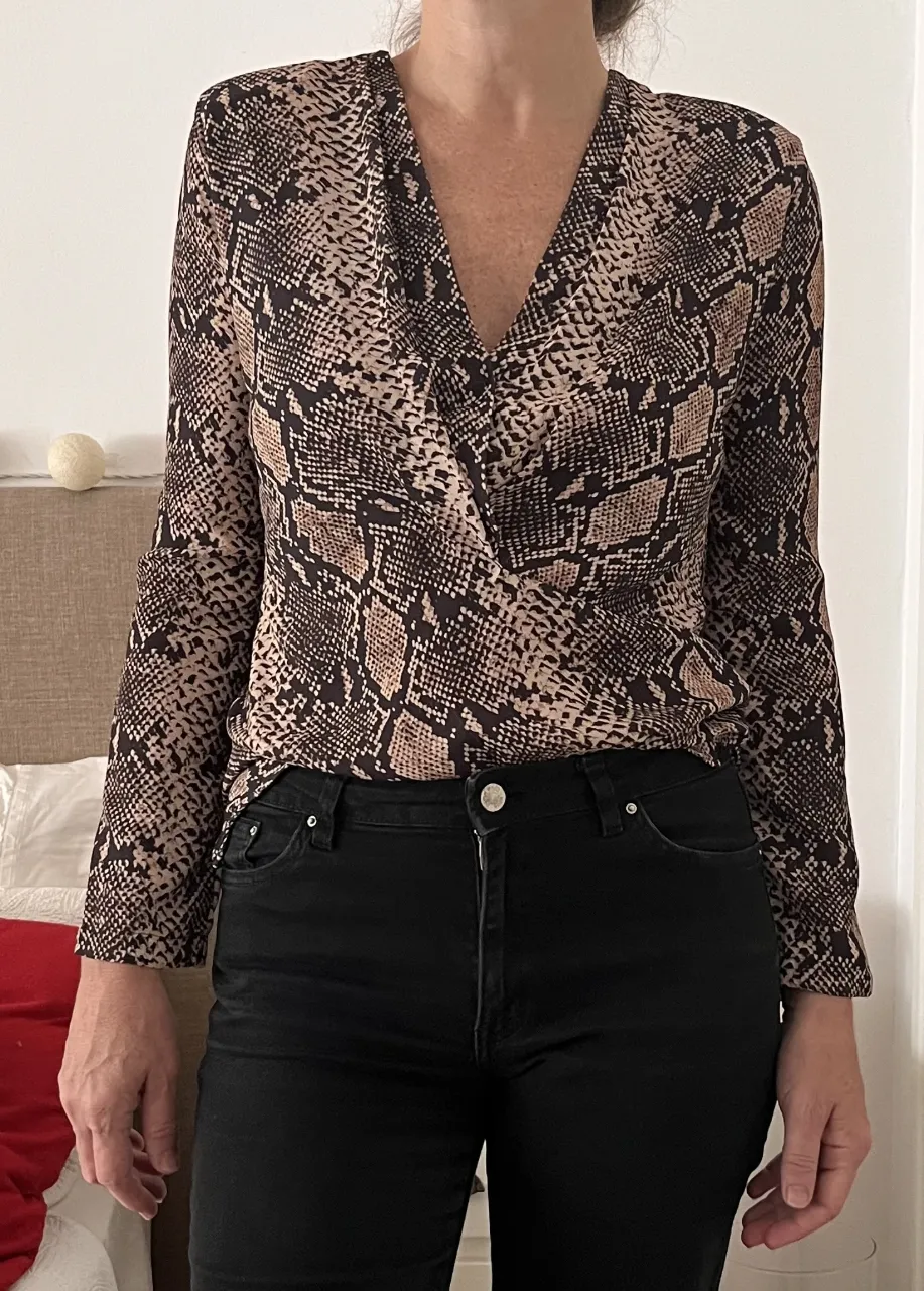 Blusa estampada con diseño de serpiente, mangas largas y escote cruzado. Ideal para un look canchero y moderno.