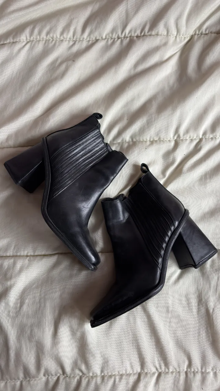 Botas negras de cuero con taco grueso y punta cuadrada. Tienen cierre lateral y elástico en los laterales.