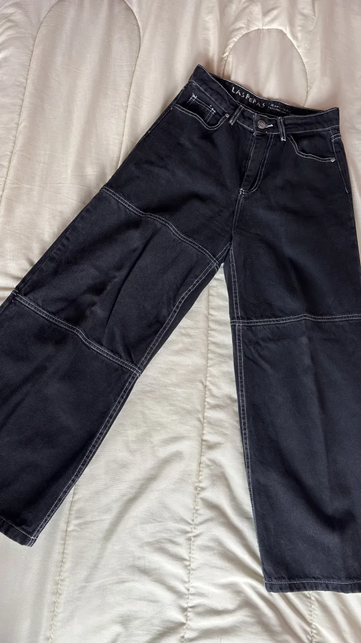 Jean negro con costuras blancas visibles. Posee bolsillos delanteros y traseros.