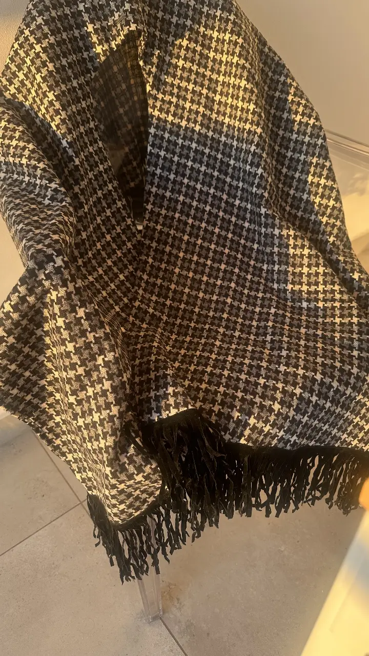 Bufanda de diseño houndstooth en blanco y negro con flecos. Ideal para complementar cualquier look de invierno.