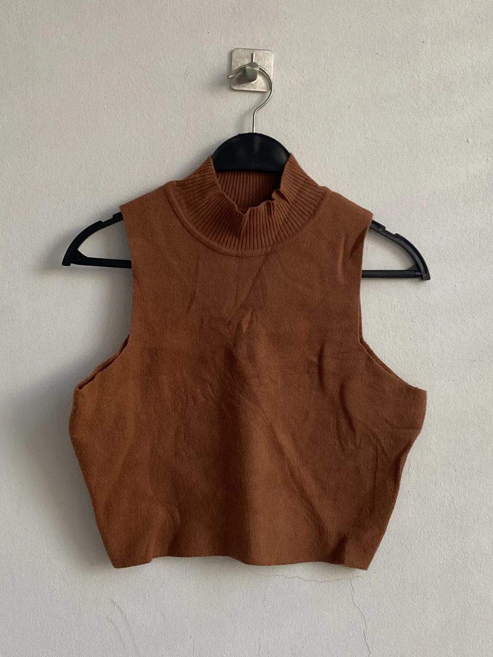 Top tejido de cuello alto y sin mangas, ideal para un look moderno y versátil. Perfecto para combinar con pantalones de cintura alta o faldas.
